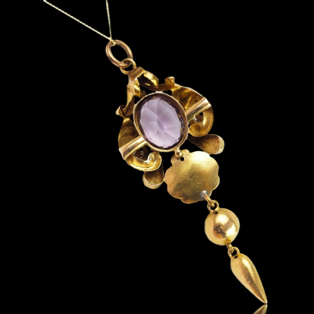 An antique 14ct yellow gold Victorian pendant featuring a central oval faceted amethyst surrounded by scrollwork, a shell motif, and an articulated drop element. View VIII