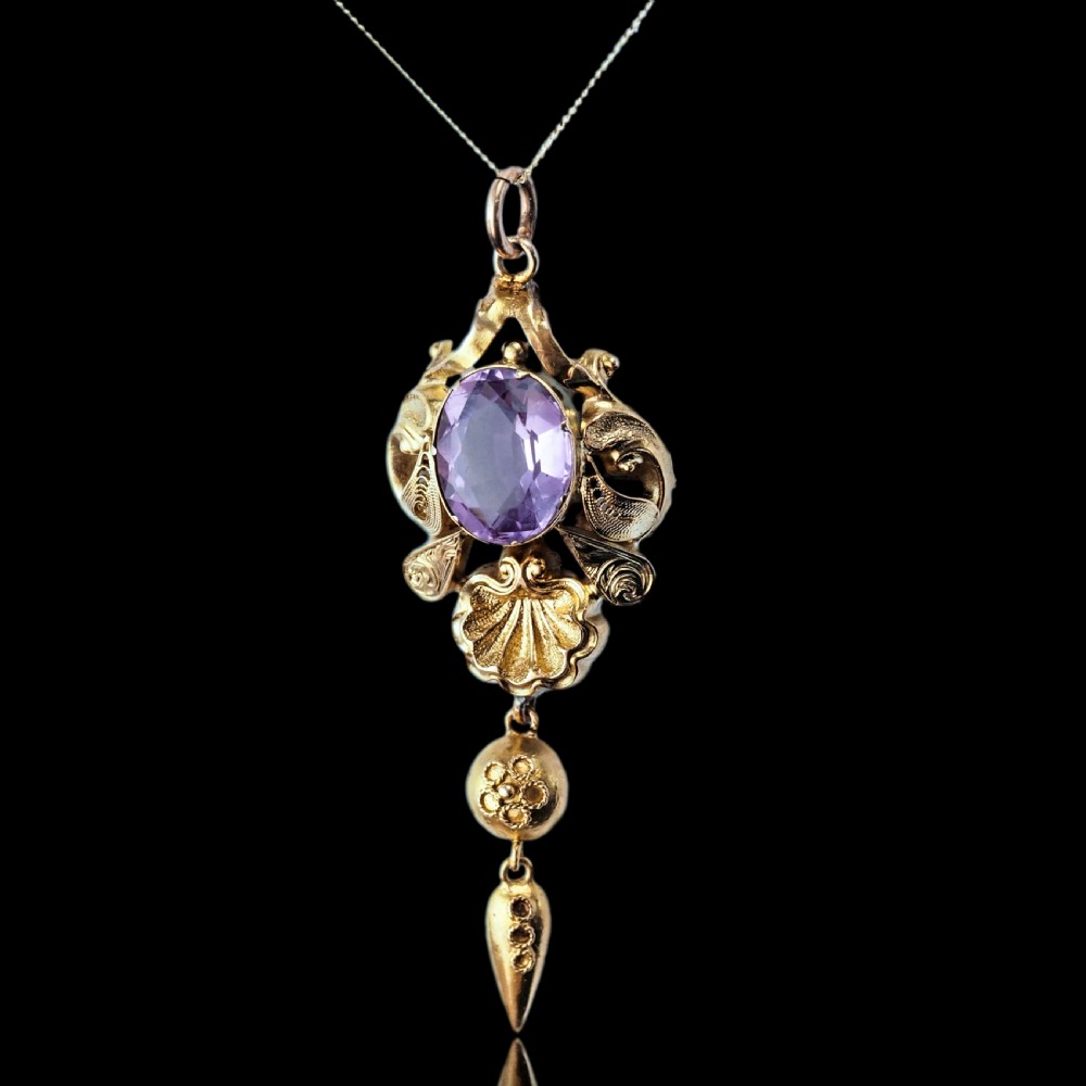 An antique 14ct yellow gold Victorian pendant featuring a central oval faceted amethyst surrounded by scrollwork, a shell motif, and an articulated drop element. View XI