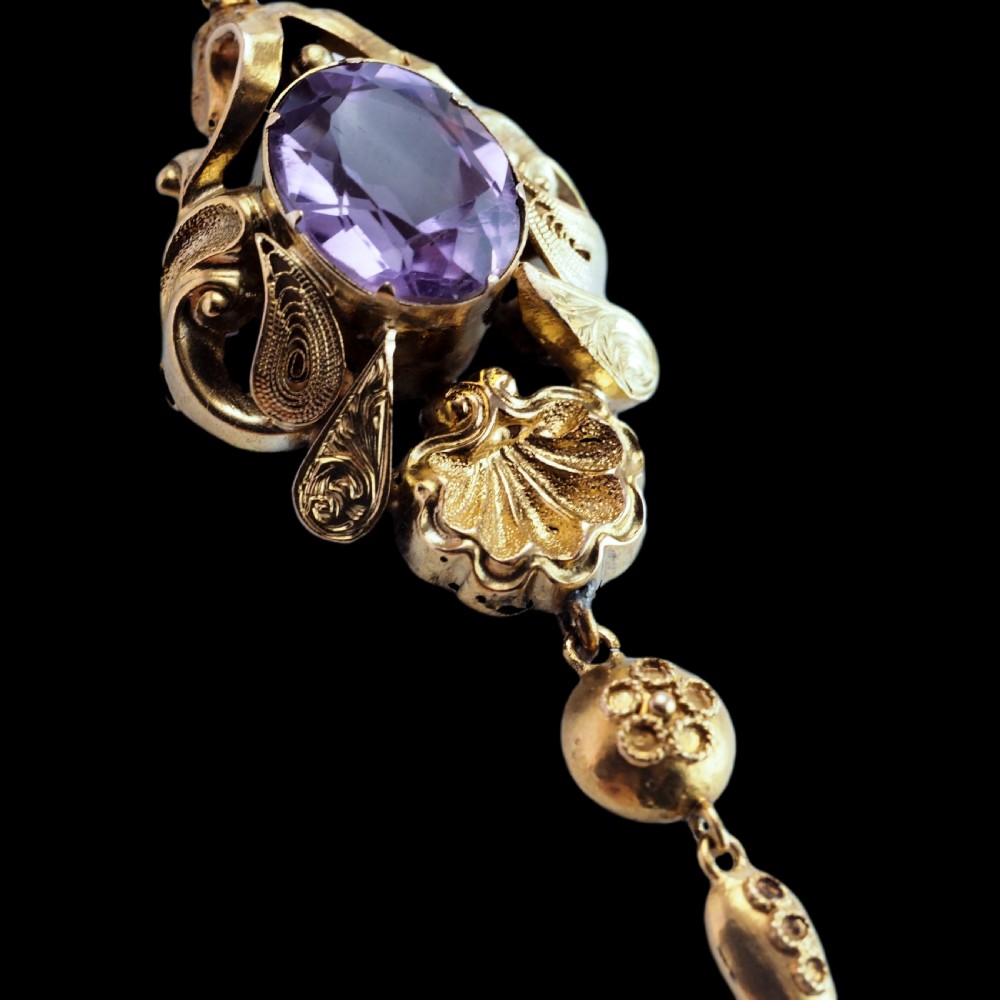 An antique 14ct yellow gold Victorian pendant featuring a central oval faceted amethyst surrounded by scrollwork, a shell motif, and an articulated drop element. View XII