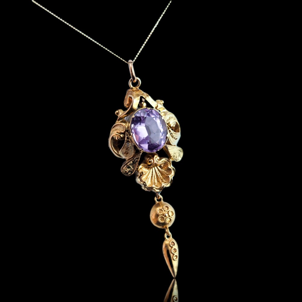 An antique 14ct yellow gold Victorian pendant featuring a central oval faceted amethyst surrounded by scrollwork, a shell motif, and an articulated drop element. View XIII