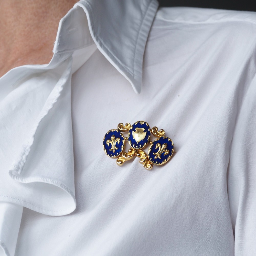 A 19th-century 18ct gold brooch featuring three dark blue enamel oval cartouches decorated with gold heraldic motifs and rococo scrollwork. View VIII