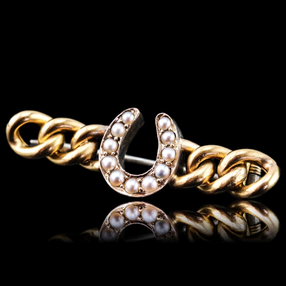 An antique 15ct gold bar brooch featuring a central horseshoe motif set with seed pearls over a curb link design. View VI