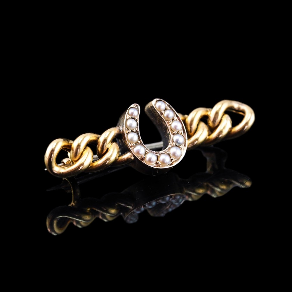 An antique 15ct gold bar brooch featuring a central horseshoe motif set with seed pearls over a curb link design. View VII