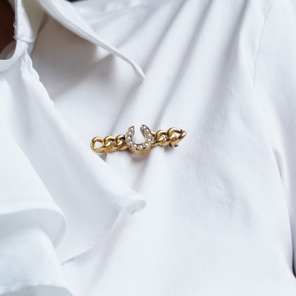 An antique 15ct gold bar brooch featuring a central horseshoe motif set with seed pearls over a curb link design. View XII