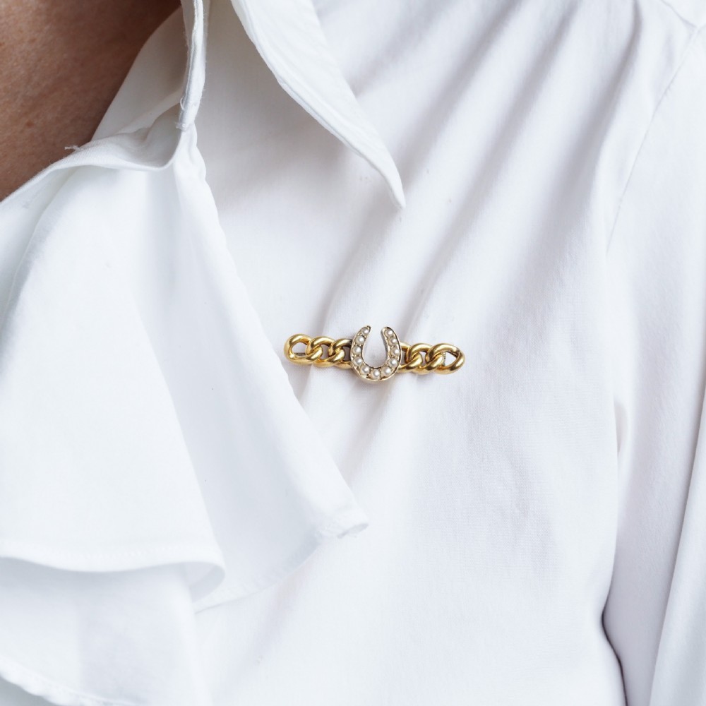 An antique 15ct gold bar brooch featuring a central horseshoe motif set with seed pearls over a curb link design. View XIII