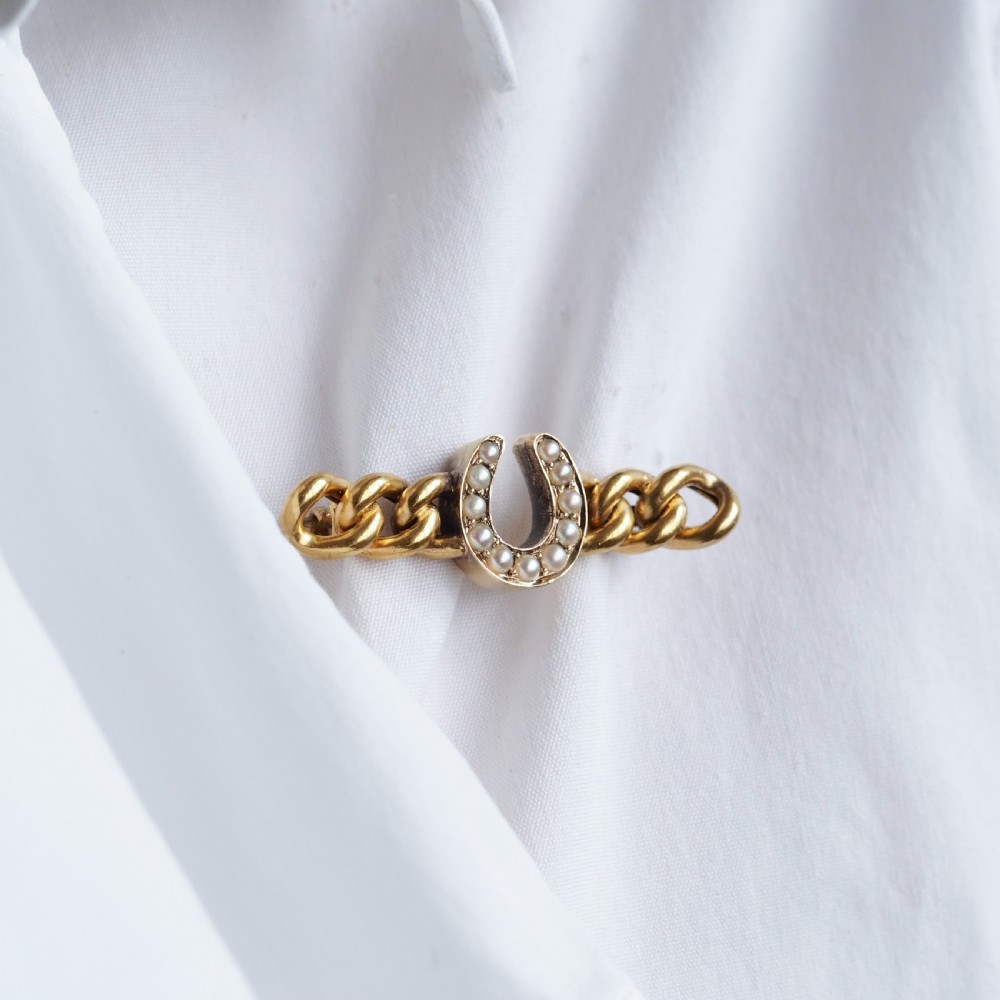 An antique 15ct gold bar brooch featuring a central horseshoe motif set with seed pearls over a curb link design. View XIV