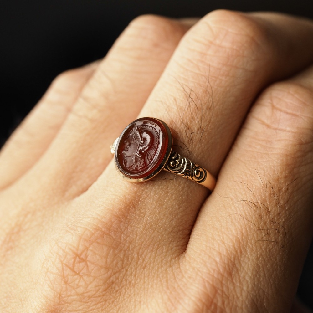 A Georgian gold ring featuring an oval reddish-brown carnelian stone engraved with the profile profile of a helmeted Roman soldier. View VI