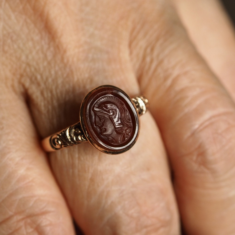 A Georgian gold ring featuring an oval reddish-brown carnelian stone engraved with the profile profile of a helmeted Roman soldier. View X