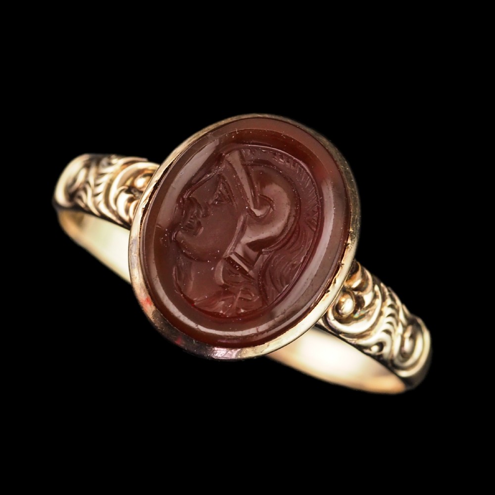 A Georgian gold ring featuring an oval reddish-brown carnelian stone engraved with the profile profile of a helmeted Roman soldier. View XI