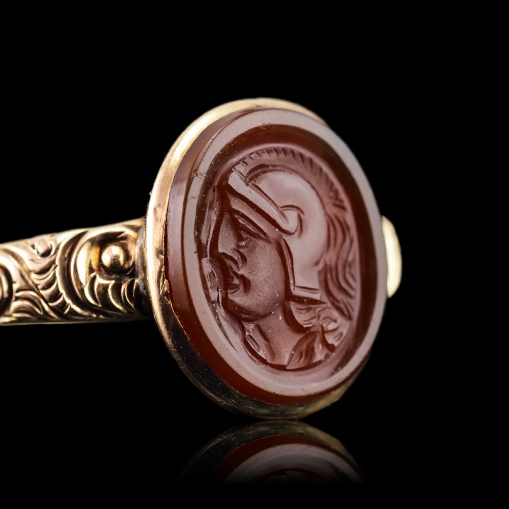 A Georgian gold ring featuring an oval reddish-brown carnelian stone engraved with the profile profile of a helmeted Roman soldier. View XIV