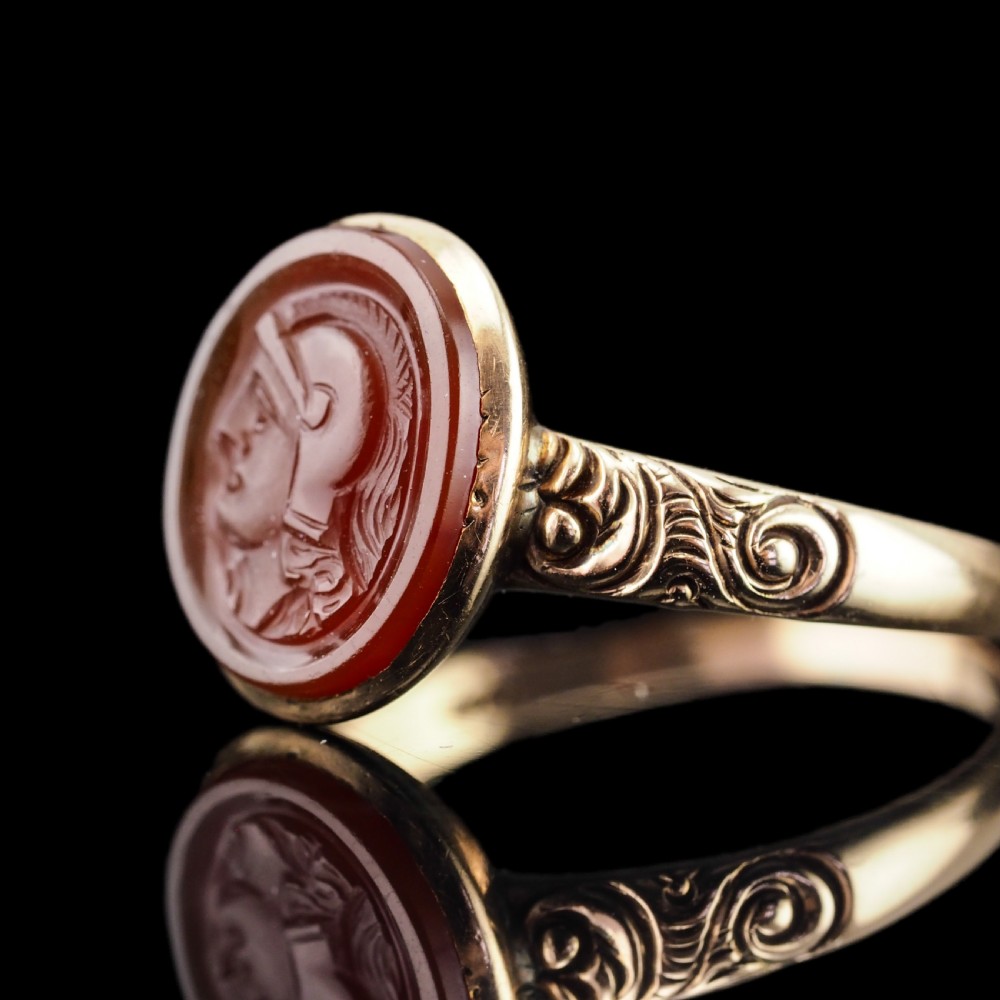 A Georgian gold ring featuring an oval reddish-brown carnelian stone engraved with the profile profile of a helmeted Roman soldier. View XVI