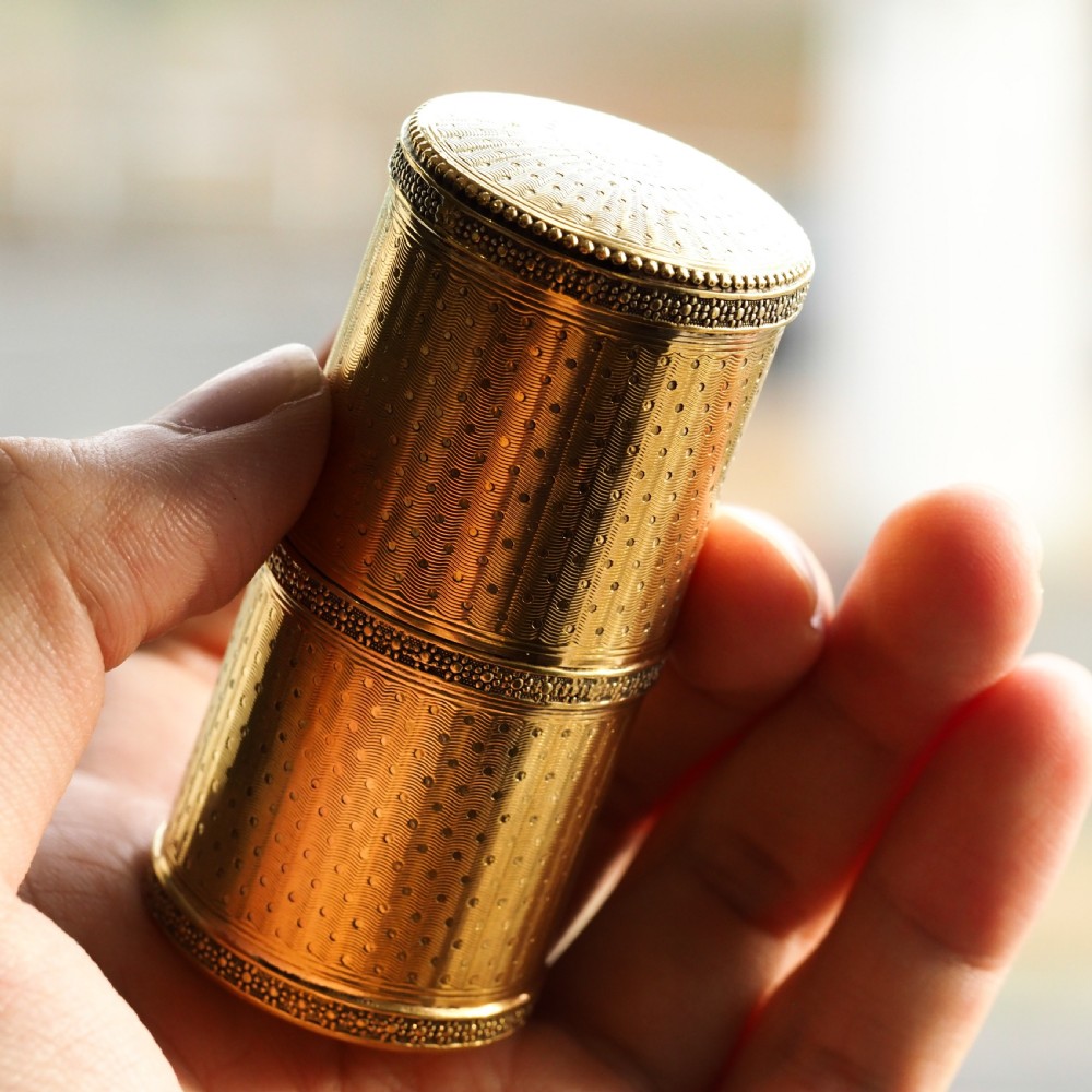 A small cylindrical French silver gilt etui featuring intricate engine-turned guilloche wave patterns and textured borders.