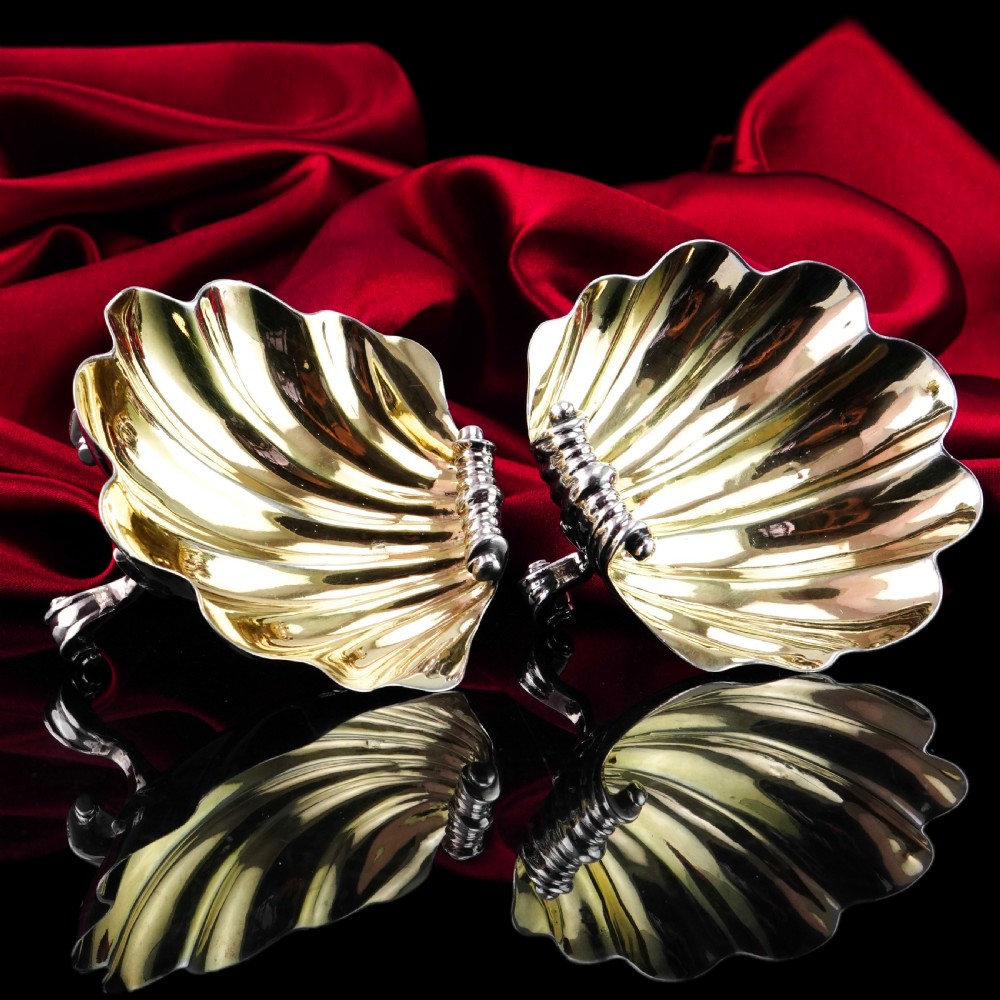 A pair of Georgian sterling silver salt cellars shaped like fluted scallop shells with gilt interiors.