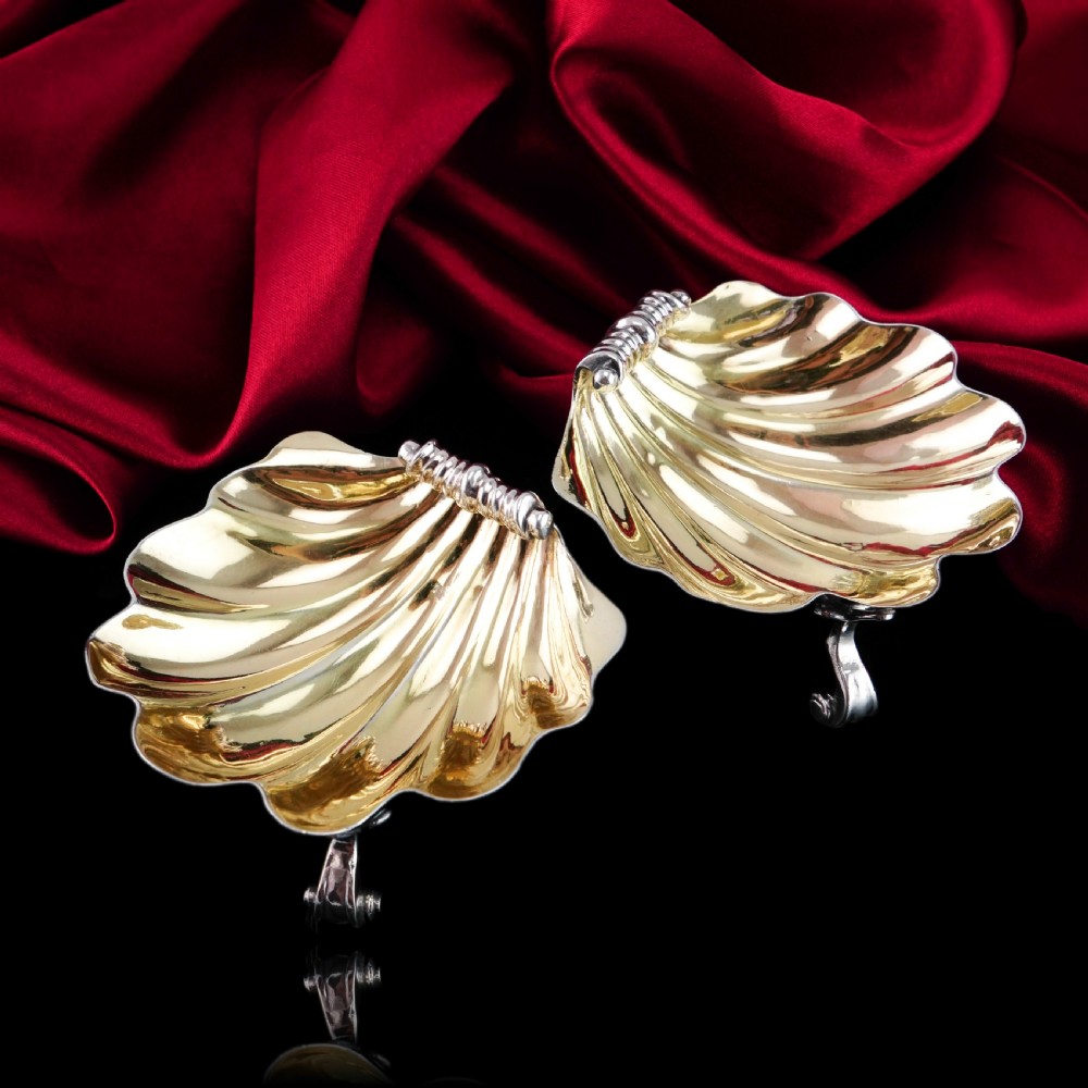 A pair of Georgian sterling silver salt cellars shaped like fluted scallop shells with gilt interiors. View V