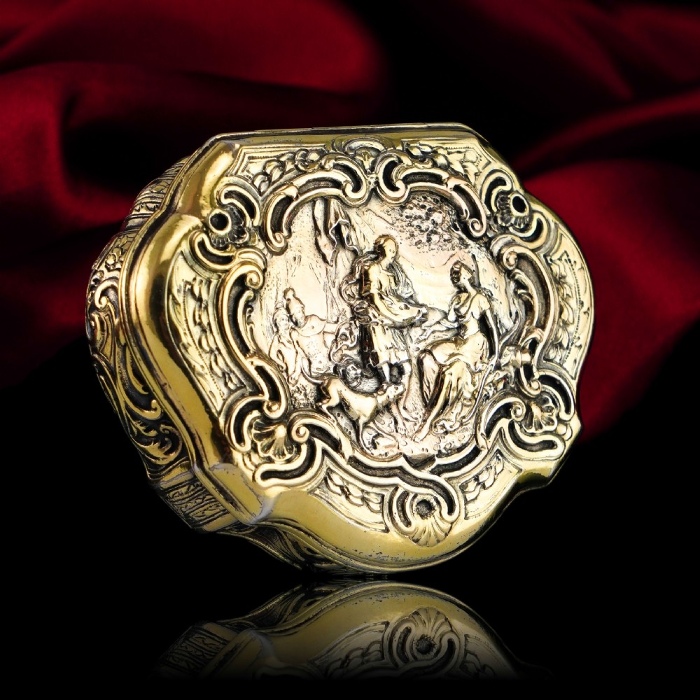 An eighteenth-century shaped oval silver-gilt table snuff box featuring Rococo scrollwork and a raised mythological scene on the hinged lid. View VI