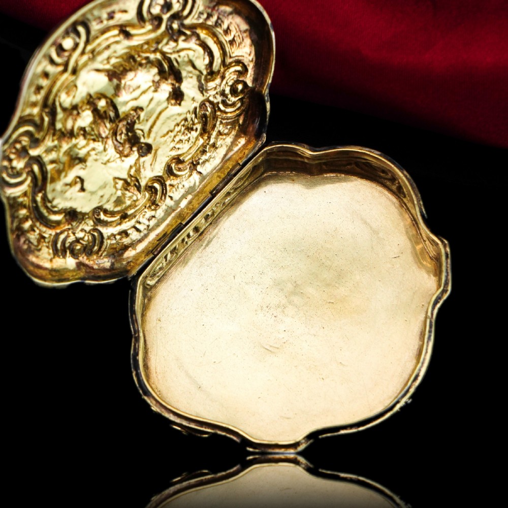 An eighteenth-century shaped oval silver-gilt table snuff box featuring Rococo scrollwork and a raised mythological scene on the hinged lid. View VII