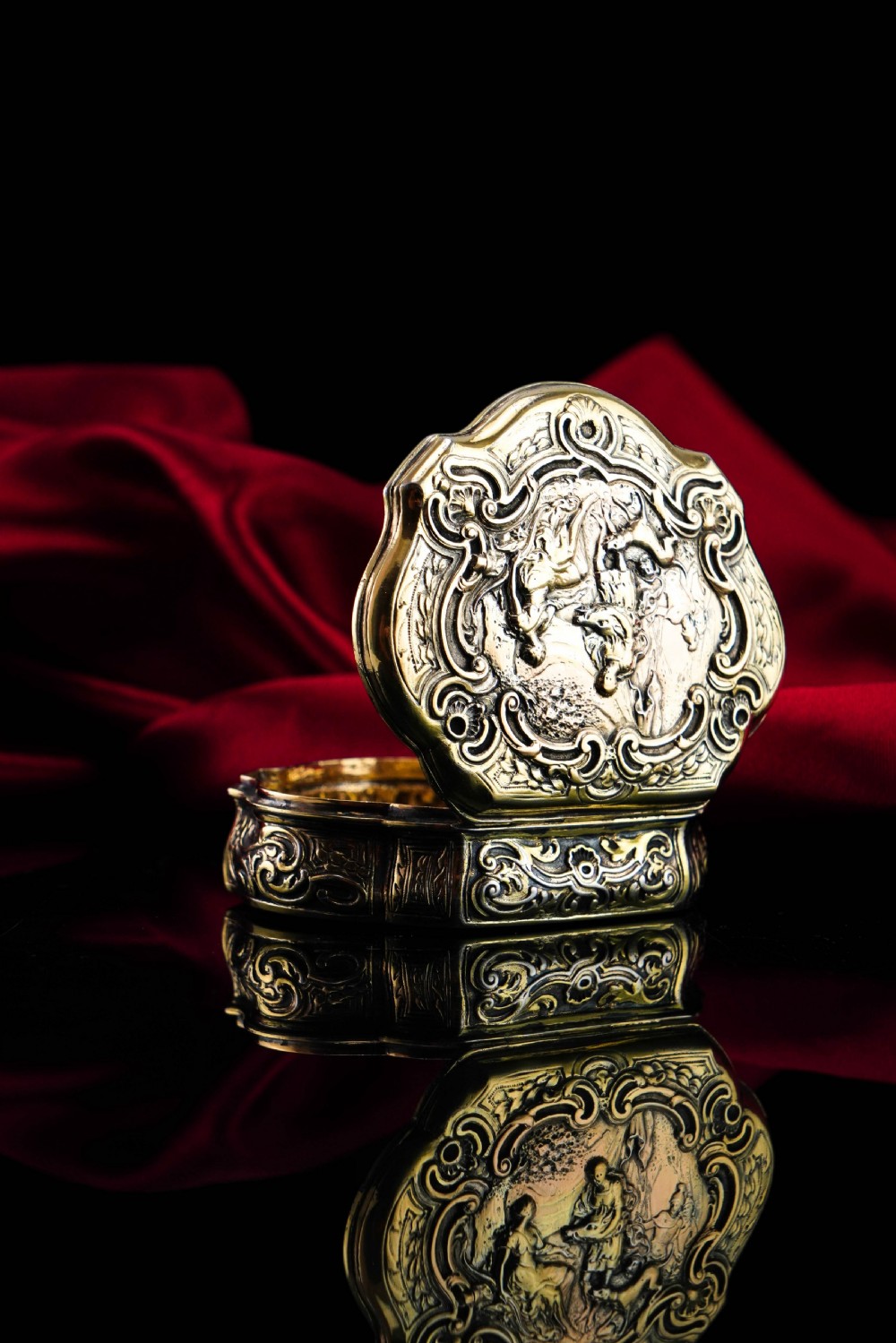 An eighteenth-century shaped oval silver-gilt table snuff box featuring Rococo scrollwork and a raised mythological scene on the hinged lid. View IX