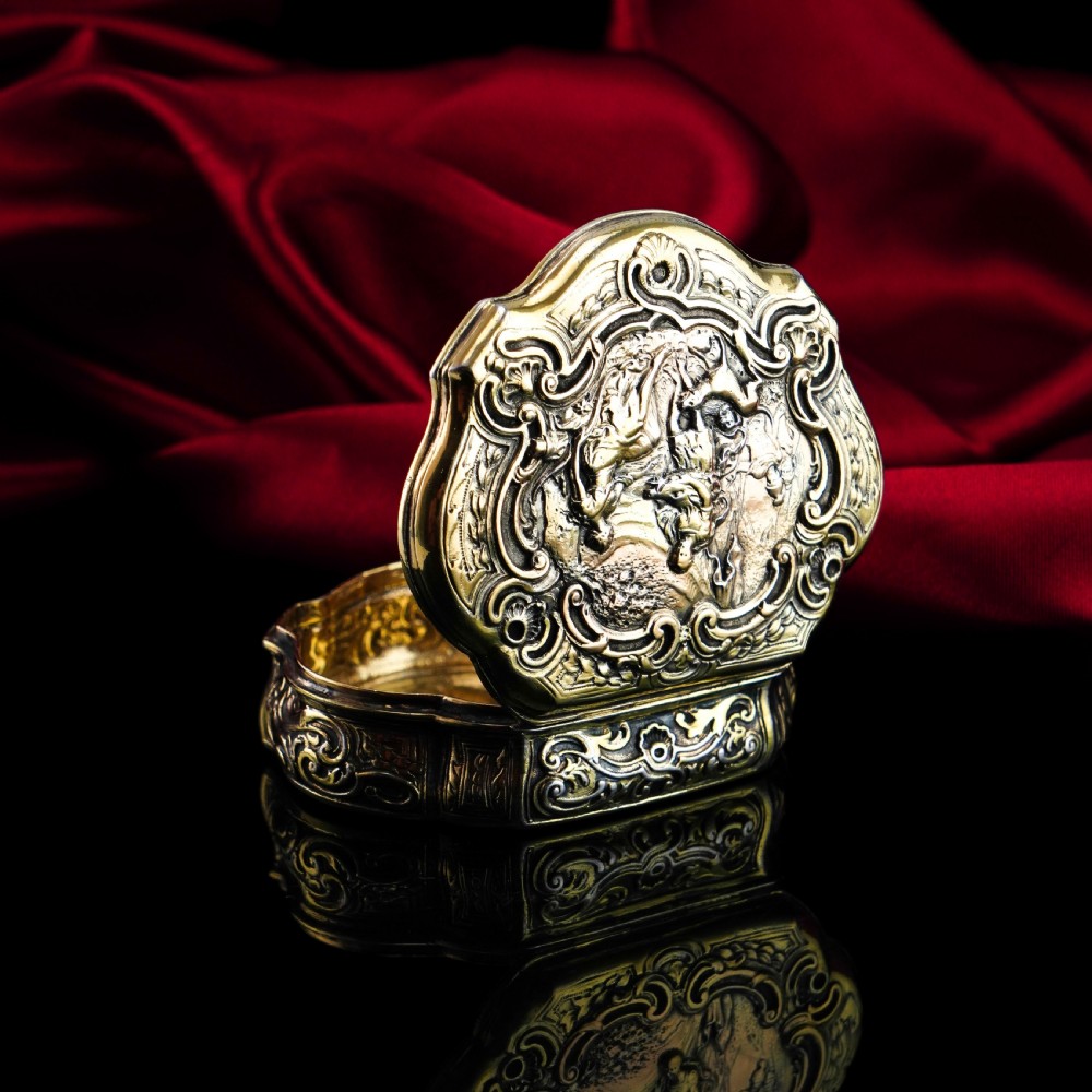 An eighteenth-century shaped oval silver-gilt table snuff box featuring Rococo scrollwork and a raised mythological scene on the hinged lid. View X