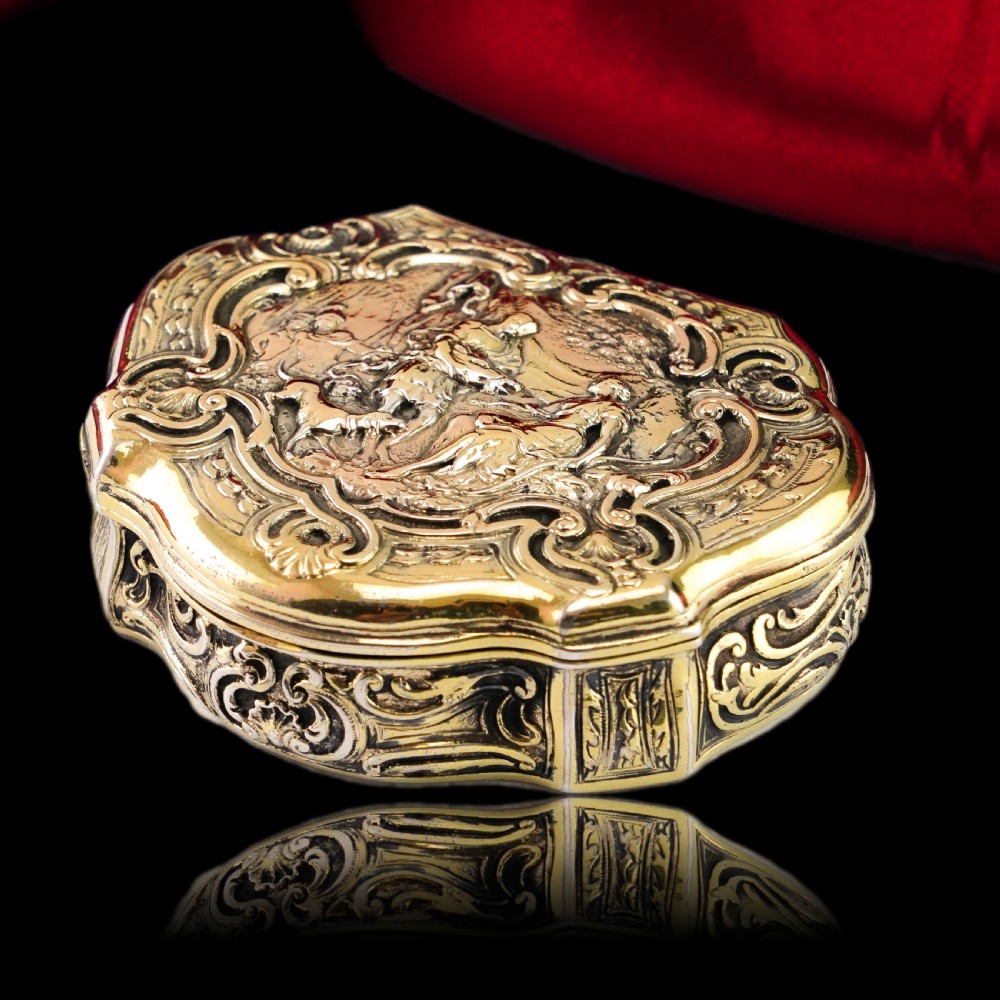 An eighteenth-century shaped oval silver-gilt table snuff box featuring Rococo scrollwork and a raised mythological scene on the hinged lid. View XI