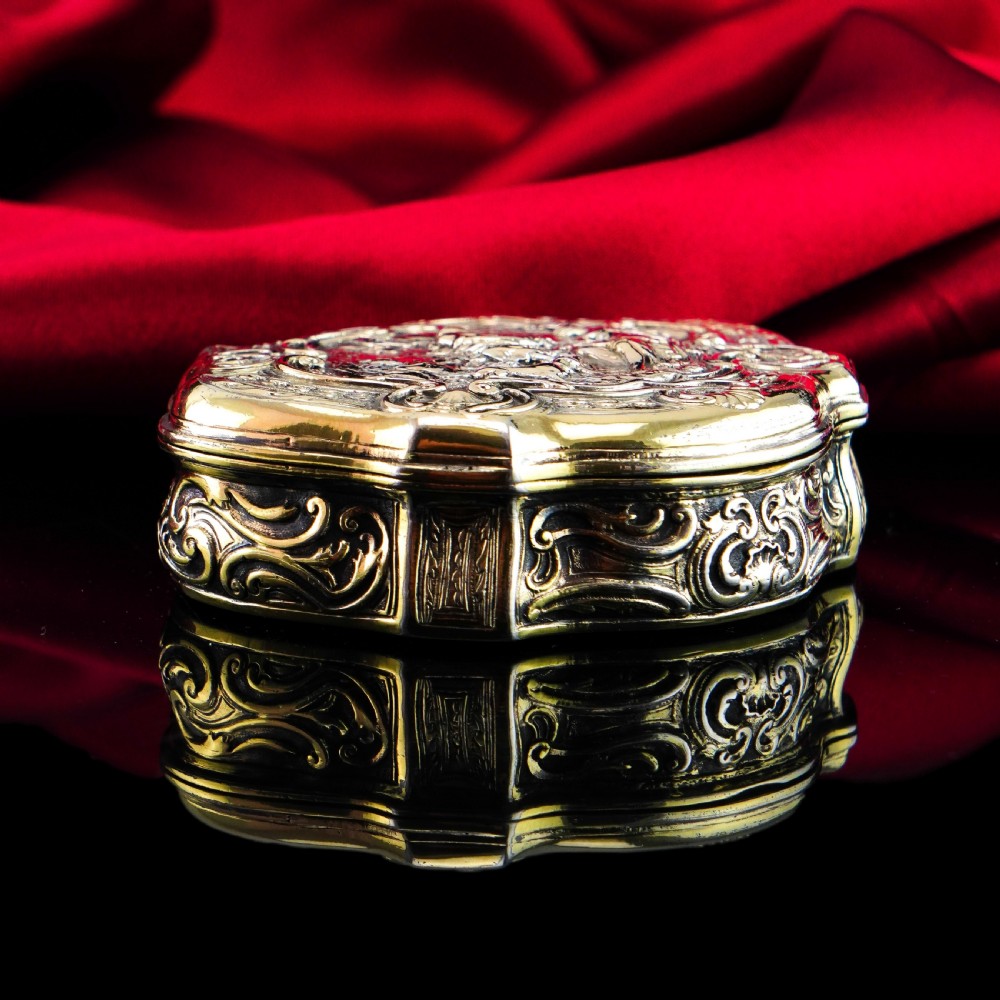 An eighteenth-century shaped oval silver-gilt table snuff box featuring Rococo scrollwork and a raised mythological scene on the hinged lid. View XII