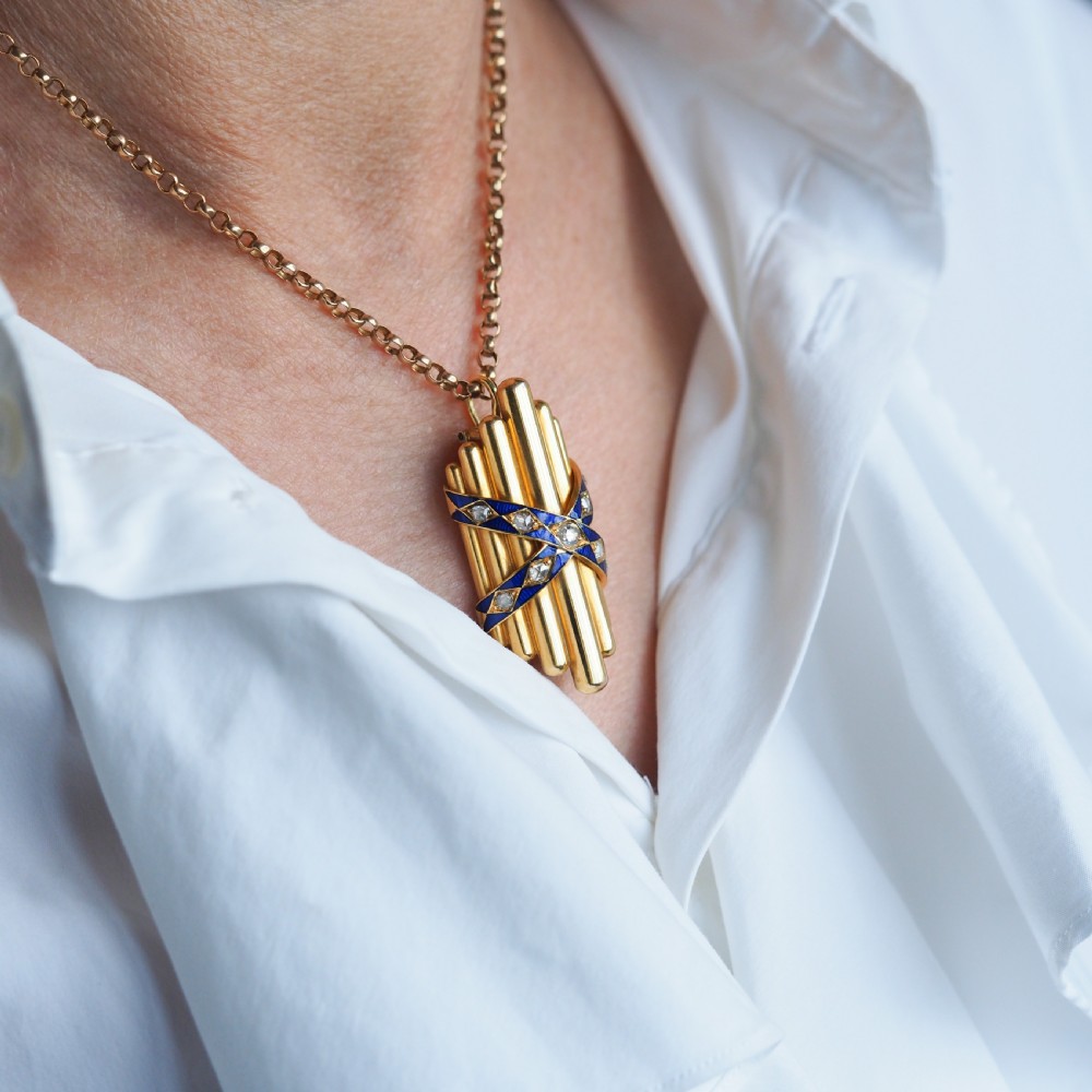 A Victorian 18K yellow gold pendant featuring vertical fluted bars encased by blue enamel cross-bands set with rose-cut diamonds. View V