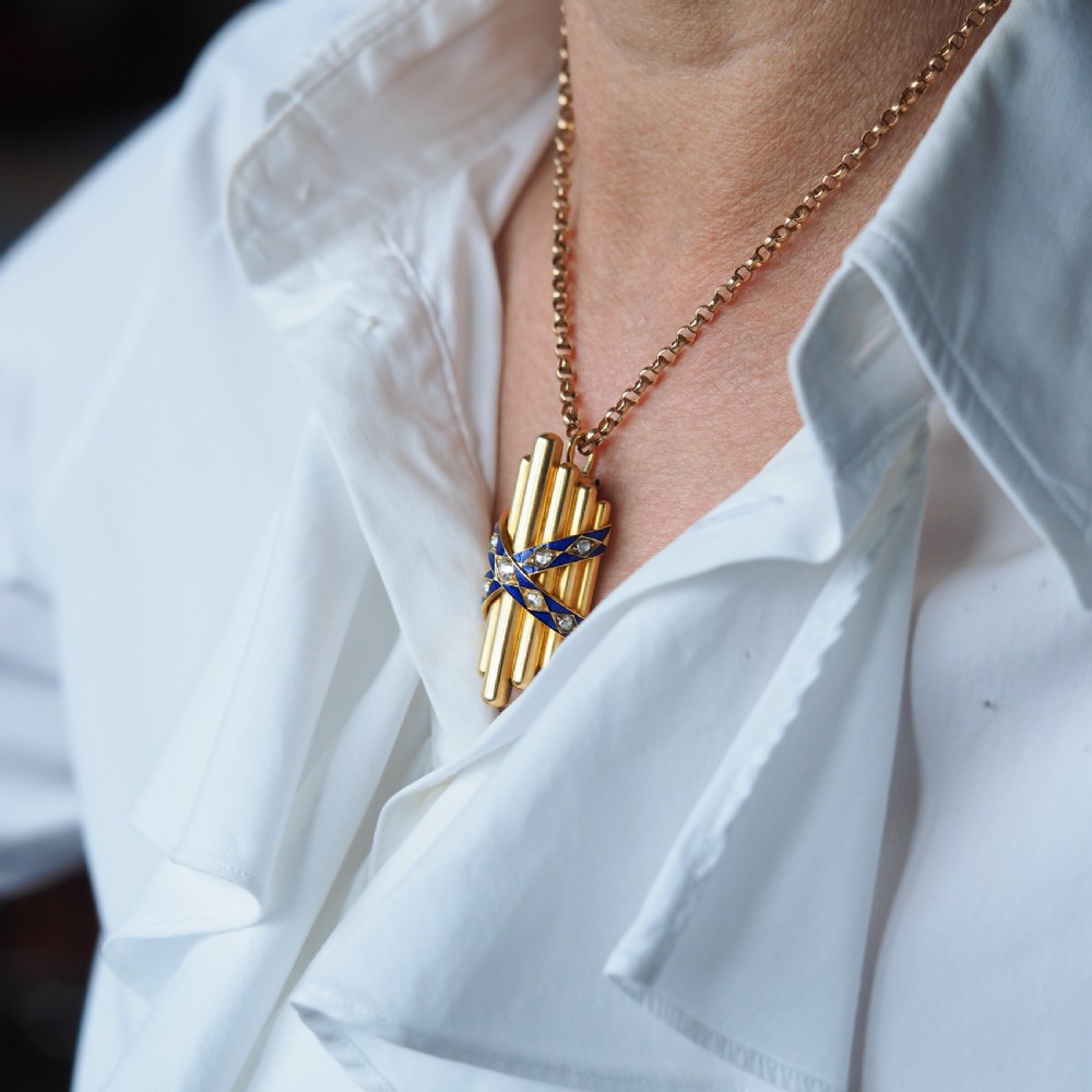 A Victorian 18K yellow gold pendant featuring vertical fluted bars encased by blue enamel cross-bands set with rose-cut diamonds. View VI
