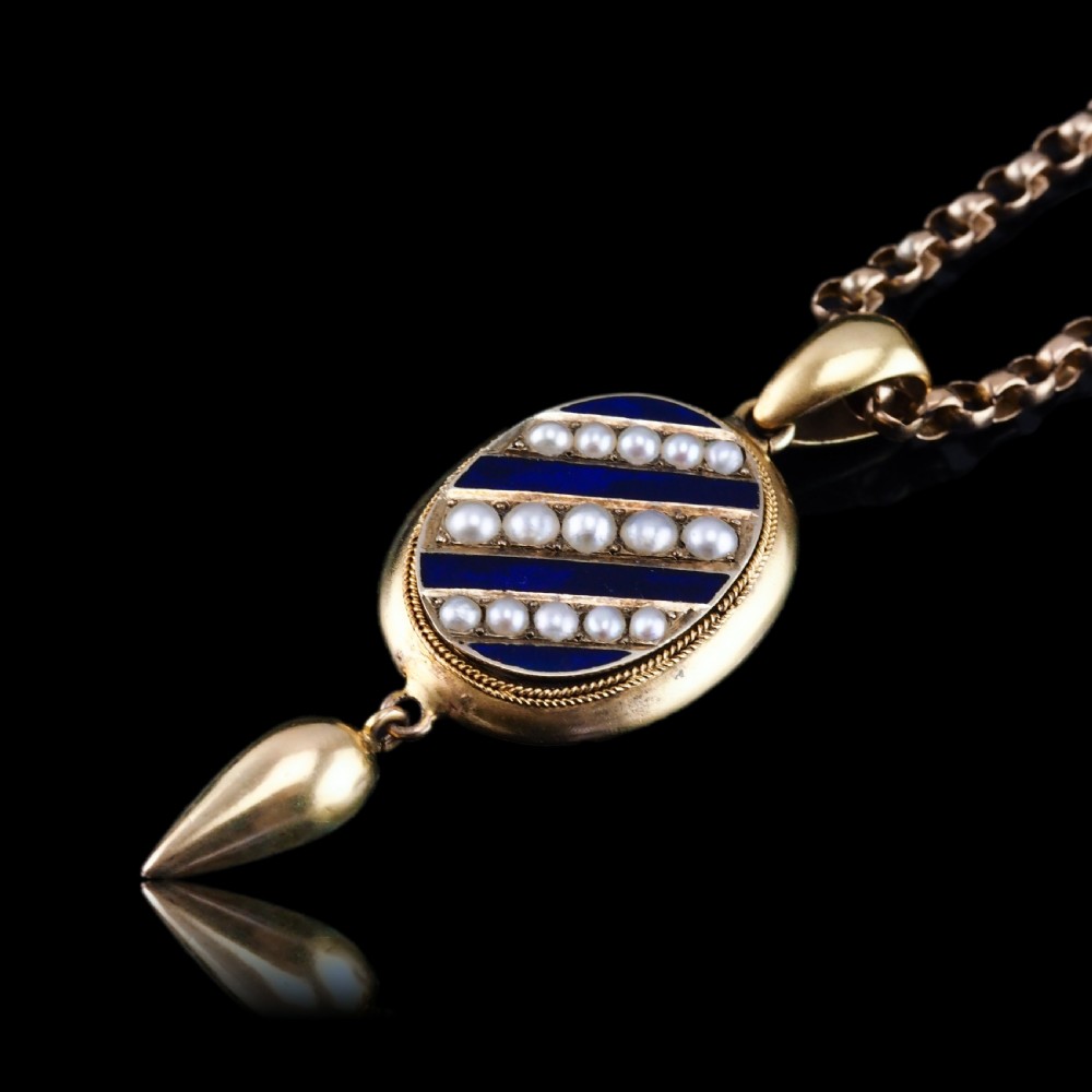 A Victorian 15ct gold oval pendant featuring diagonal stripes of royal blue enamel and seed pearls with a suspended gold drop. View VII