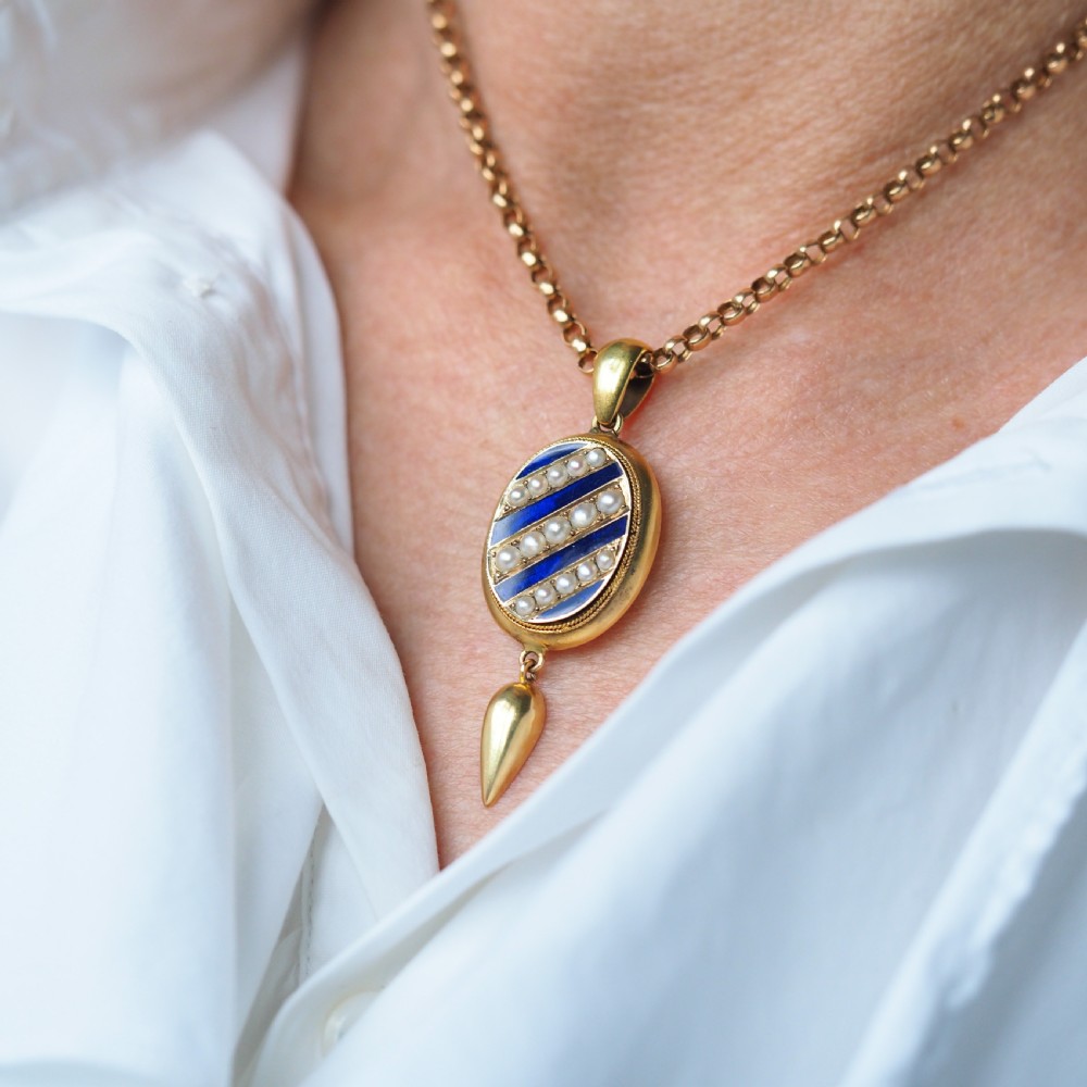 A Victorian 15ct gold oval pendant featuring diagonal stripes of royal blue enamel and seed pearls with a suspended gold drop. View VIII