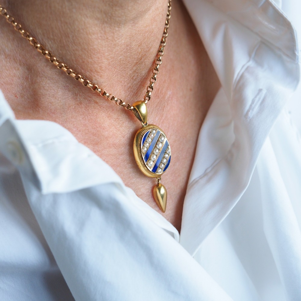 A Victorian 15ct gold oval pendant featuring diagonal stripes of royal blue enamel and seed pearls with a suspended gold drop. View XI
