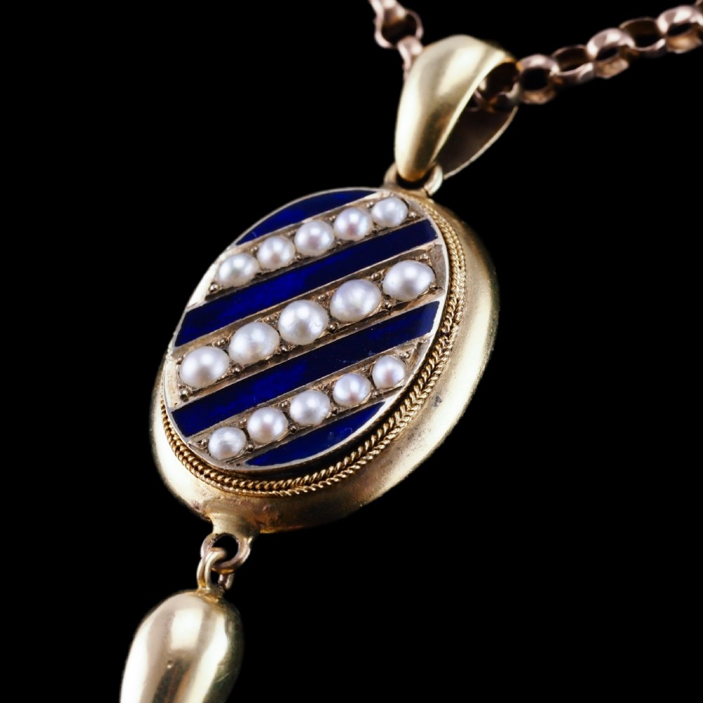 A Victorian 15ct gold oval pendant featuring diagonal stripes of royal blue enamel and seed pearls with a suspended gold drop. View XII