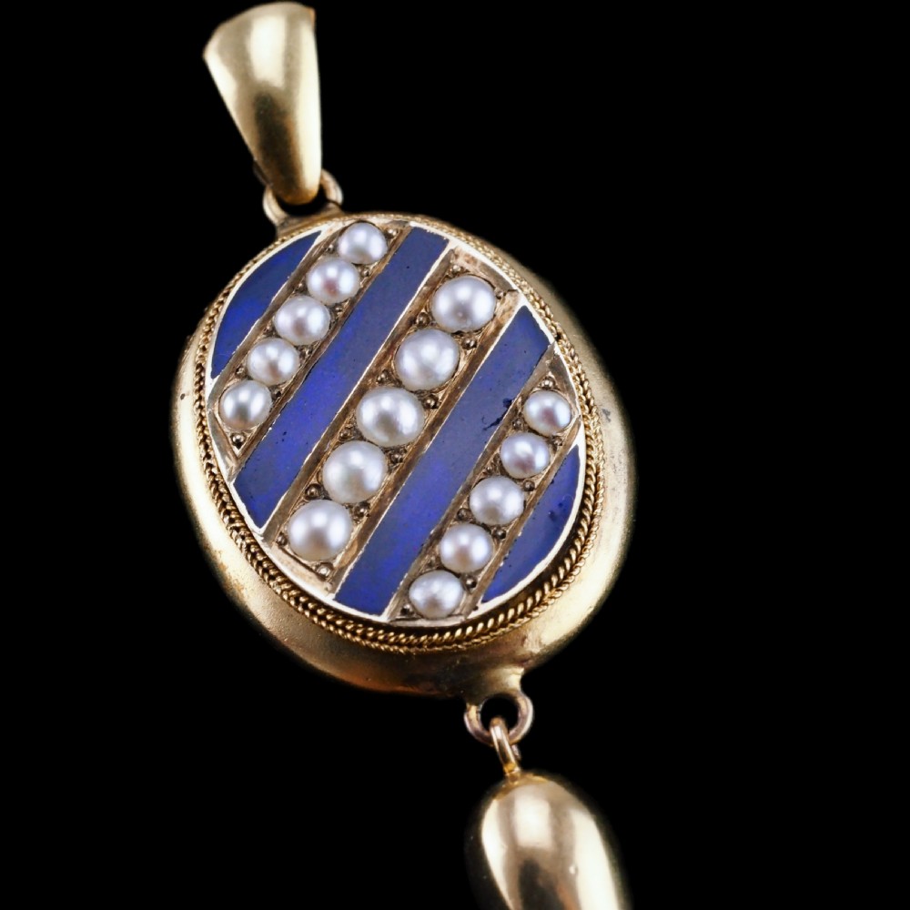 A Victorian 15ct gold oval pendant featuring diagonal stripes of royal blue enamel and seed pearls with a suspended gold drop. View XIII