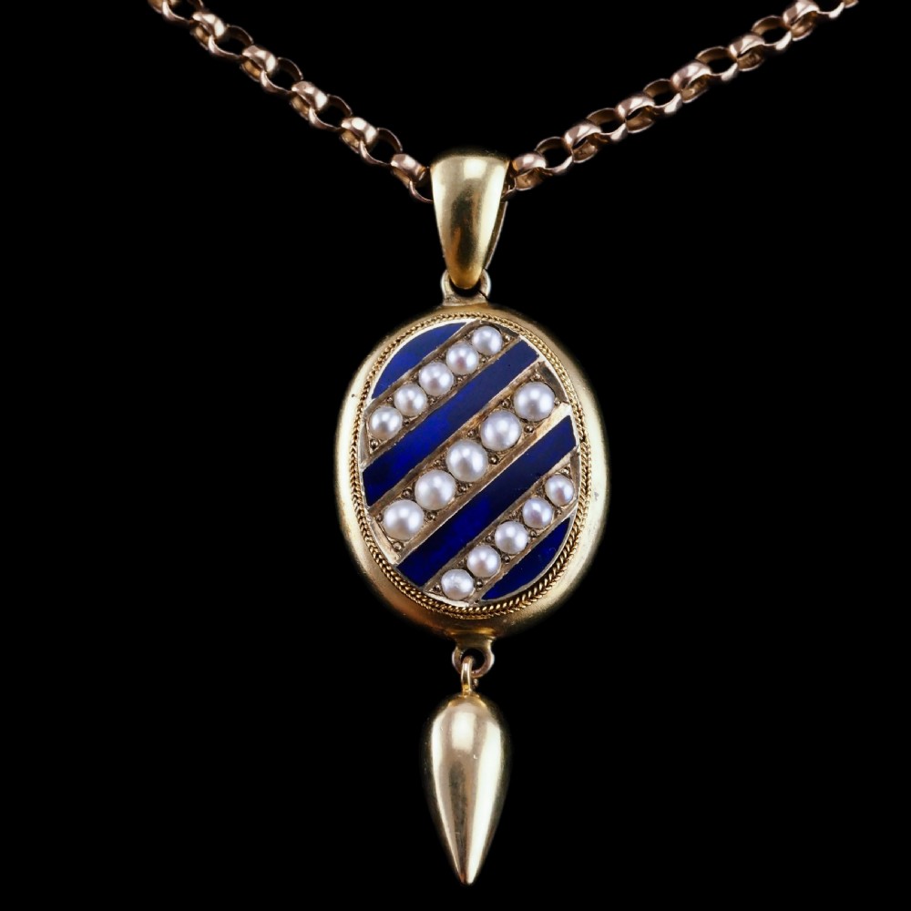 A Victorian 15ct gold oval pendant featuring diagonal stripes of royal blue enamel and seed pearls with a suspended gold drop. View XIV