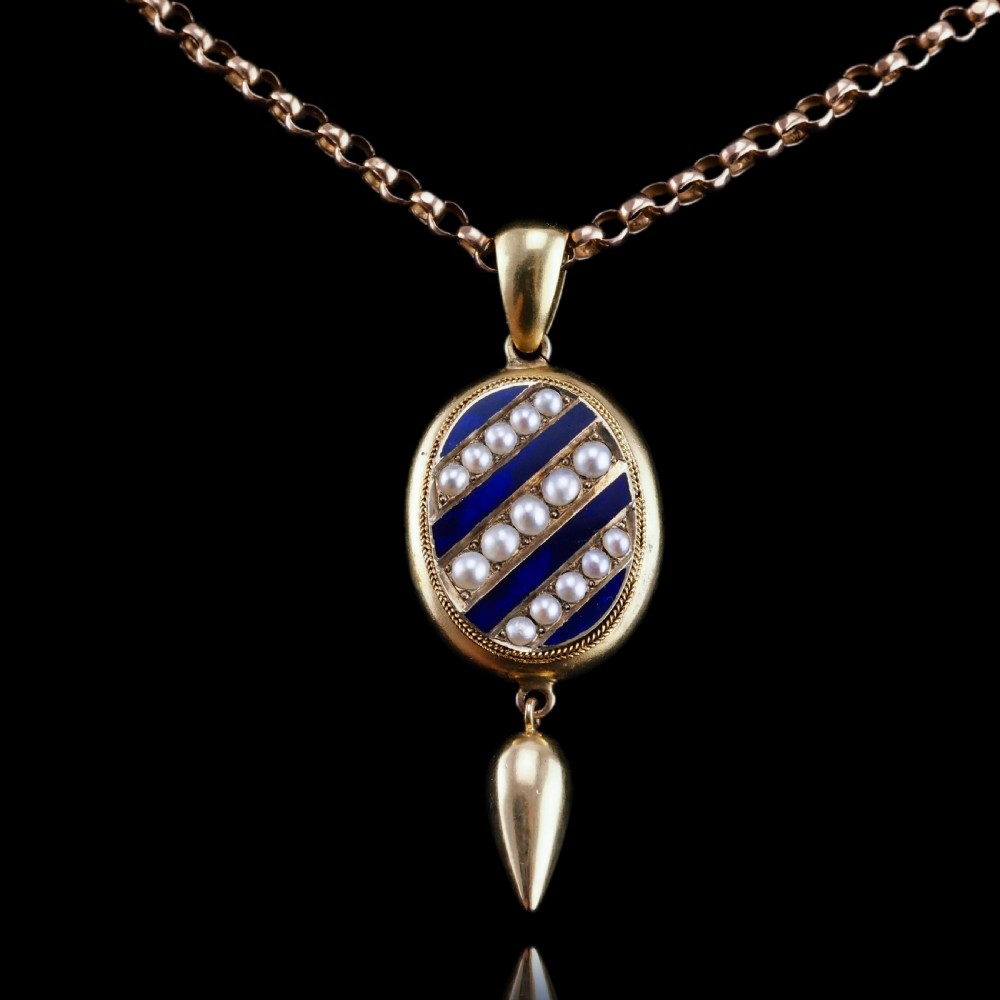A Victorian 15ct gold oval pendant featuring diagonal stripes of royal blue enamel and seed pearls with a suspended gold drop. View XV