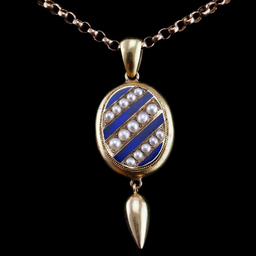 A Victorian 15ct gold oval pendant featuring diagonal stripes of royal blue enamel and seed pearls with a suspended gold drop. View XVI