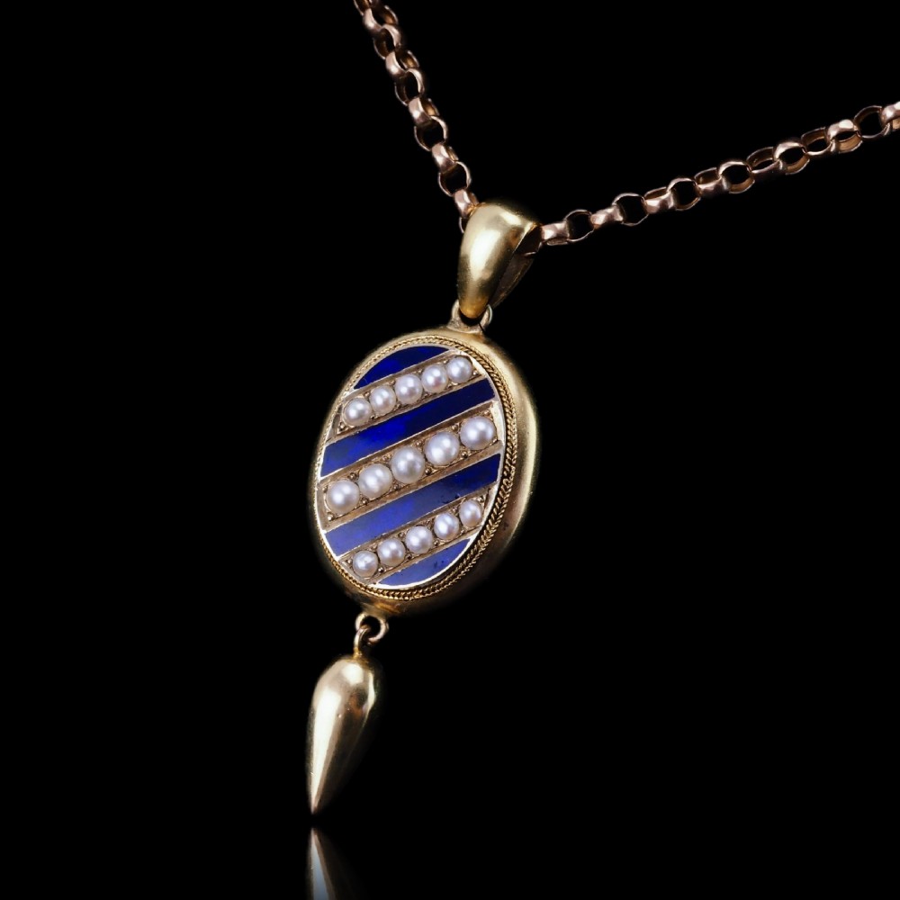 A Victorian 15ct gold oval pendant featuring diagonal stripes of royal blue enamel and seed pearls with a suspended gold drop. View XVII