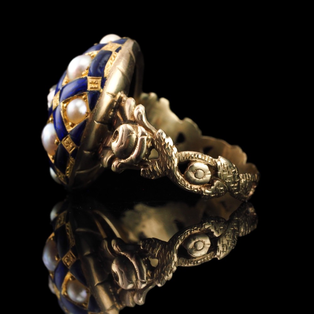 An antique Victorian 14K gold ring featuring a domed royal blue enamel lattice design accented with round pearls, star engravings, and a central diamond. View IX