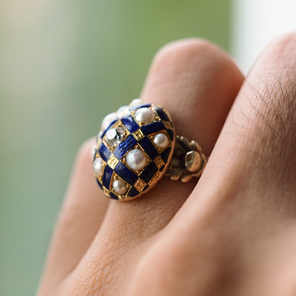 An antique Victorian 14K gold ring featuring a domed royal blue enamel lattice design accented with round pearls, star engravings, and a central diamond. View XV