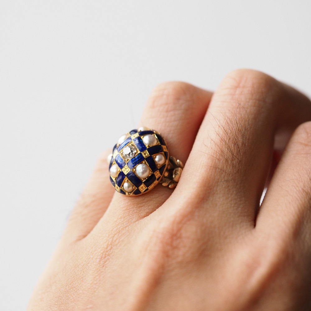 An antique Victorian 14K gold ring featuring a domed royal blue enamel lattice design accented with round pearls, star engravings, and a central diamond. View XVII