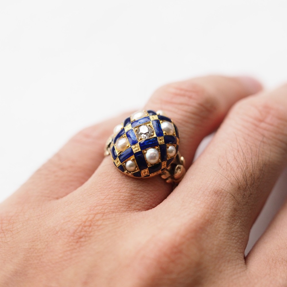An antique Victorian 14K gold ring featuring a domed royal blue enamel lattice design accented with round pearls, star engravings, and a central diamond. View XVIII