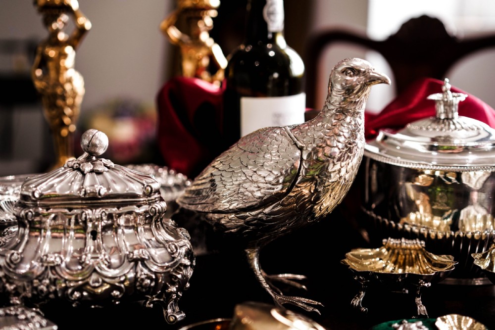 A solid silver model of a partridge with chased feather detailing standing on two feet with a hinged compartment lid along its back. View VII