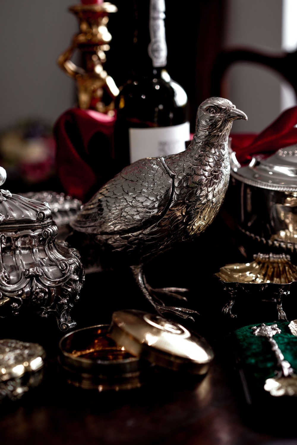 A solid silver model of a partridge with chased feather detailing standing on two feet with a hinged compartment lid along its back. View VIII