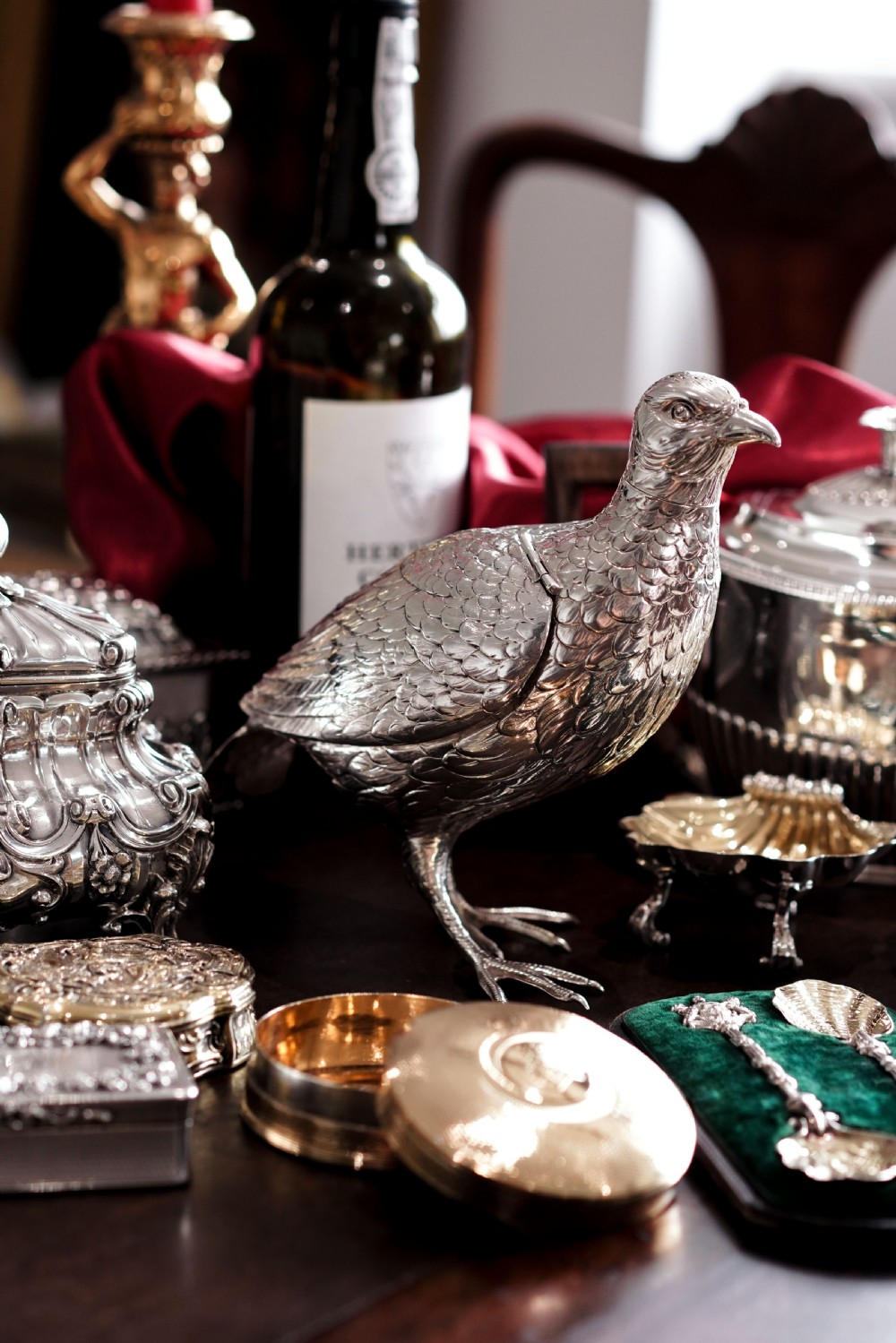 A solid silver model of a partridge with chased feather detailing standing on two feet with a hinged compartment lid along its back. View X