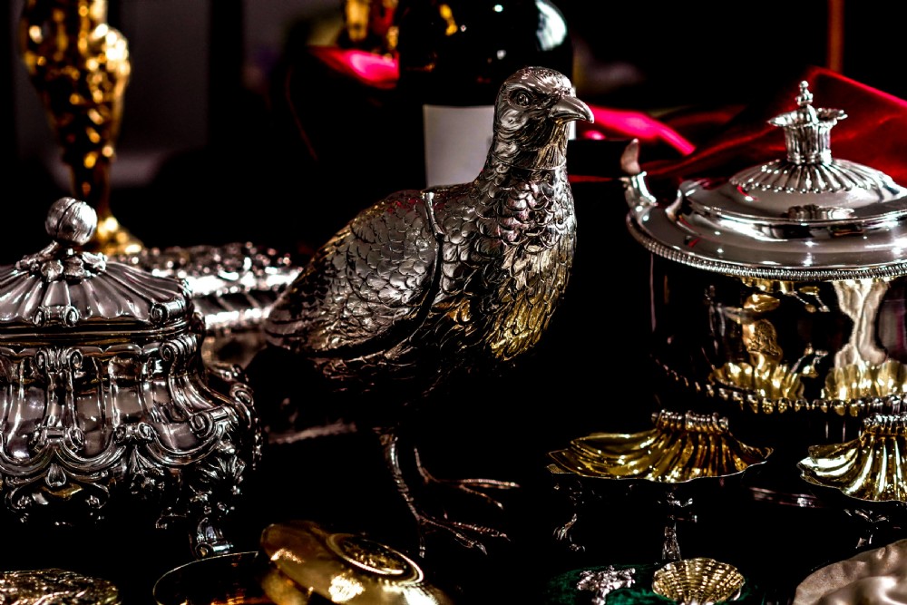 A solid silver model of a partridge with chased feather detailing standing on two feet with a hinged compartment lid along its back. View XIII