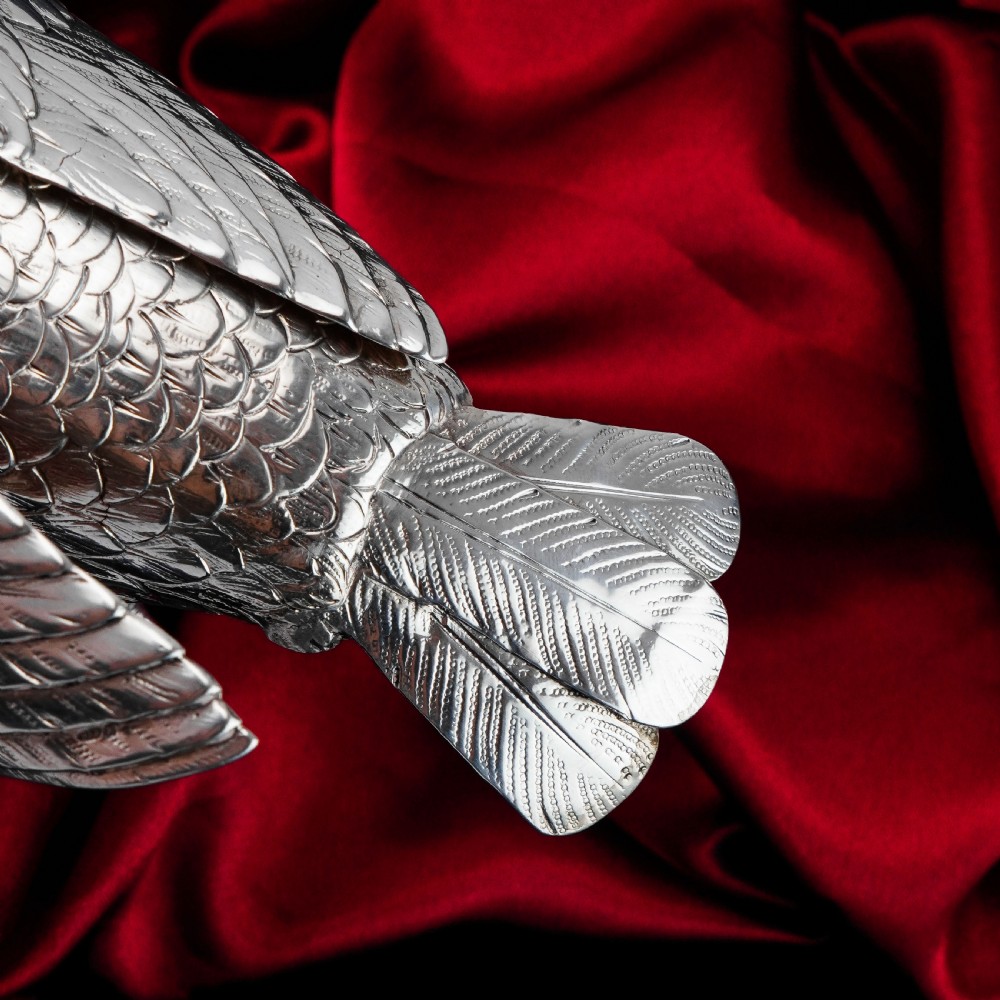 A solid silver model of a partridge with chased feather detailing standing on two feet with a hinged compartment lid along its back. View XV