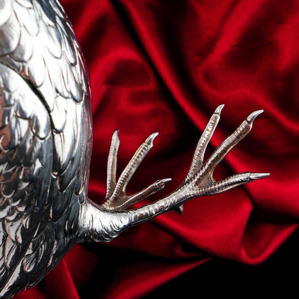 A solid silver model of a partridge with chased feather detailing standing on two feet with a hinged compartment lid along its back. View XVI