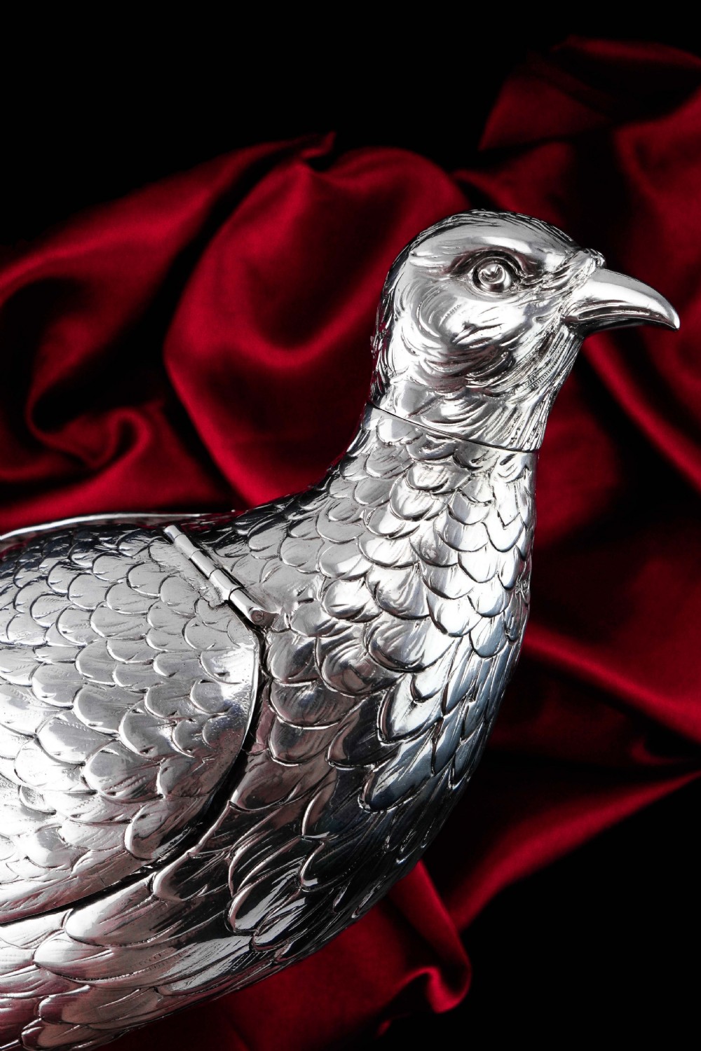 A solid silver model of a partridge with chased feather detailing standing on two feet with a hinged compartment lid along its back. View XVII