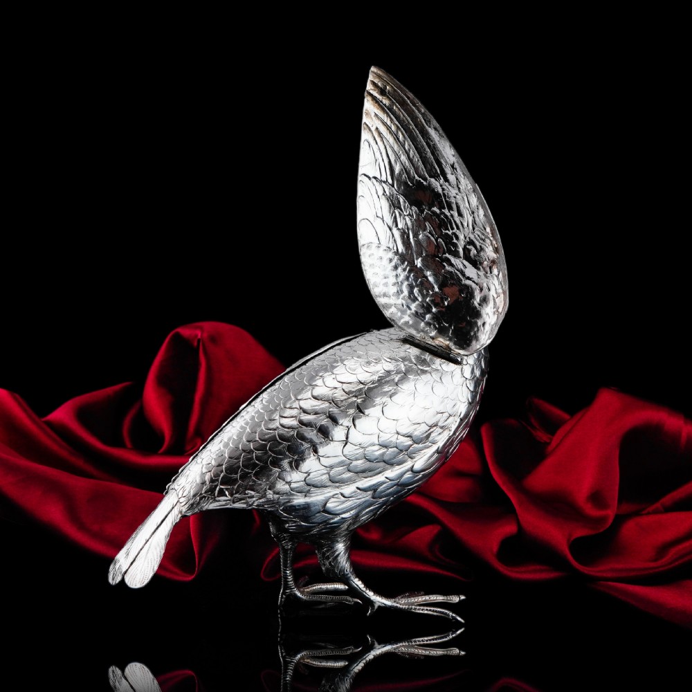 A solid silver model of a partridge with chased feather detailing standing on two feet with a hinged compartment lid along its back. View XXII