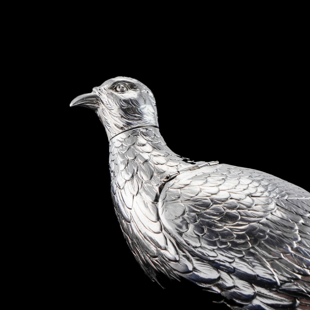 A solid silver model of a partridge with chased feather detailing standing on two feet with a hinged compartment lid along its back. View XXIV