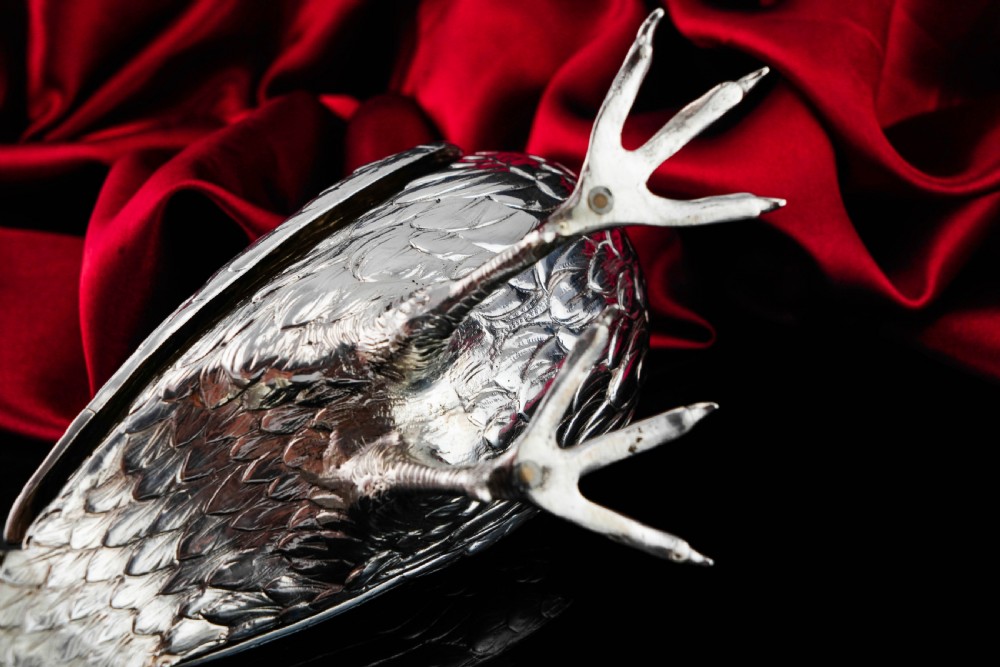 A solid silver model of a partridge with chased feather detailing standing on two feet with a hinged compartment lid along its back. View XXV