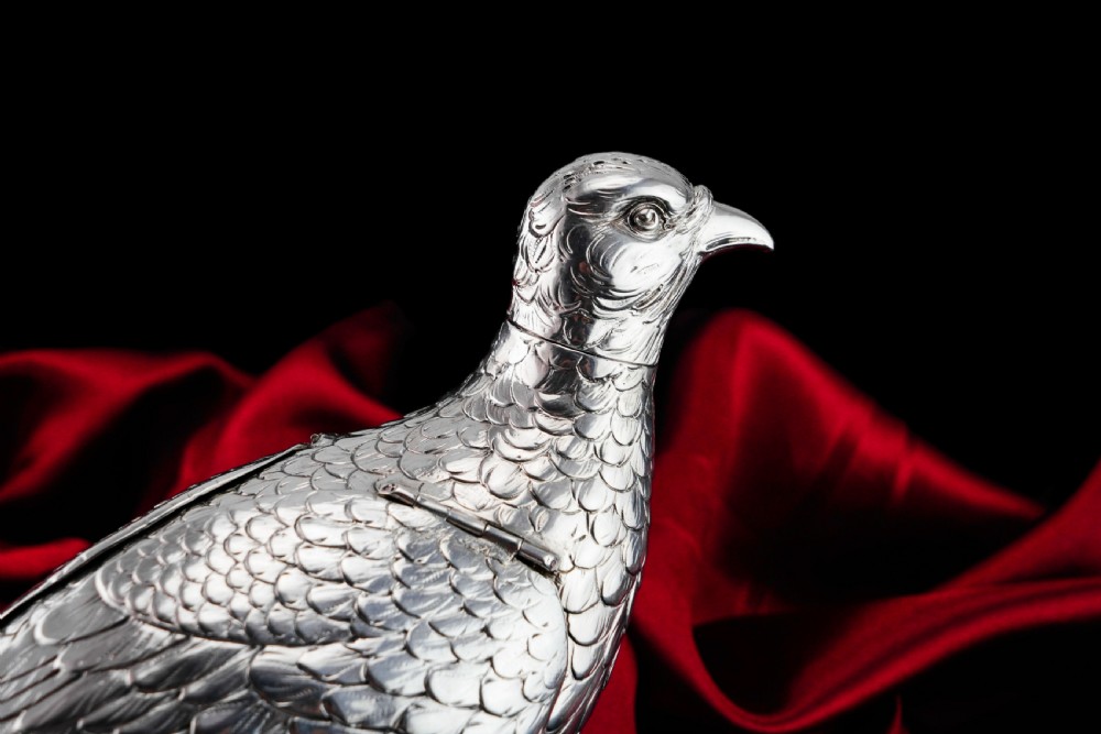 A solid silver model of a partridge with chased feather detailing standing on two feet with a hinged compartment lid along its back. View XXVI